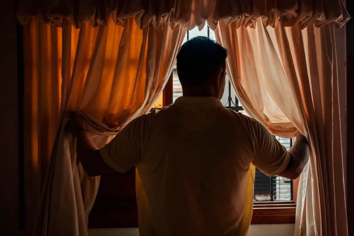 Andry Omar Blanco Bonilla mira por la ventana de su casa.